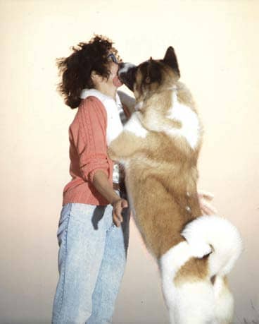 Dog standing on two legs licking a woman's face