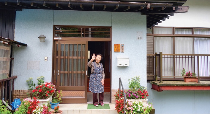 Japanese woman standing in front of an entrance to a house