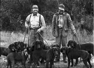 Two unidentified members of the Plott family with their hounds before a hunt. 