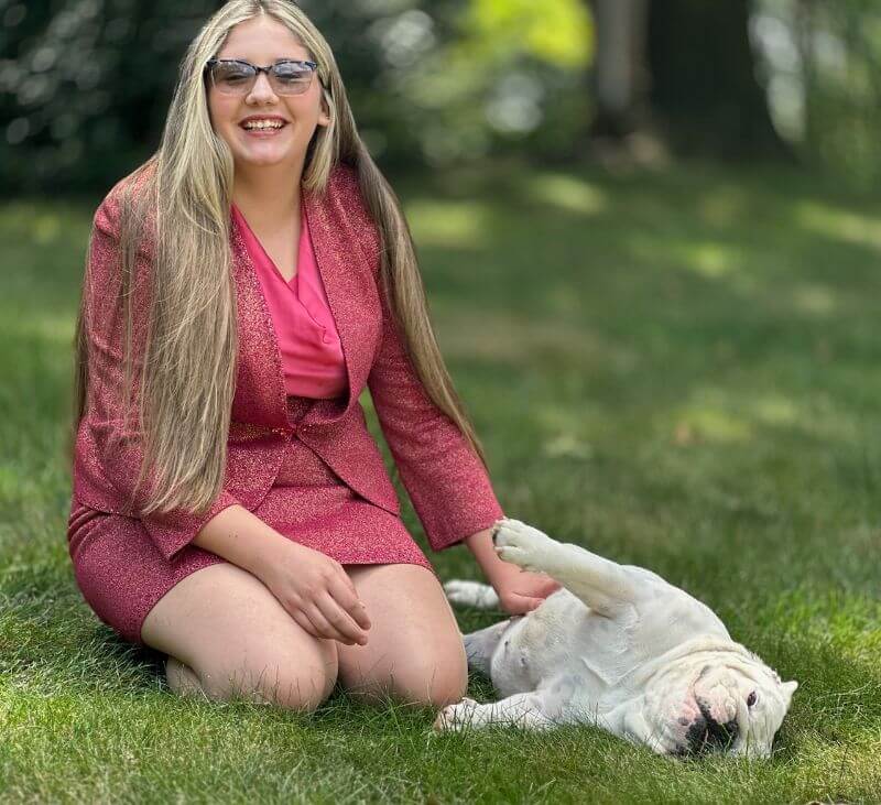 Zoe Brewer sitting on grass with her Bulldog.
